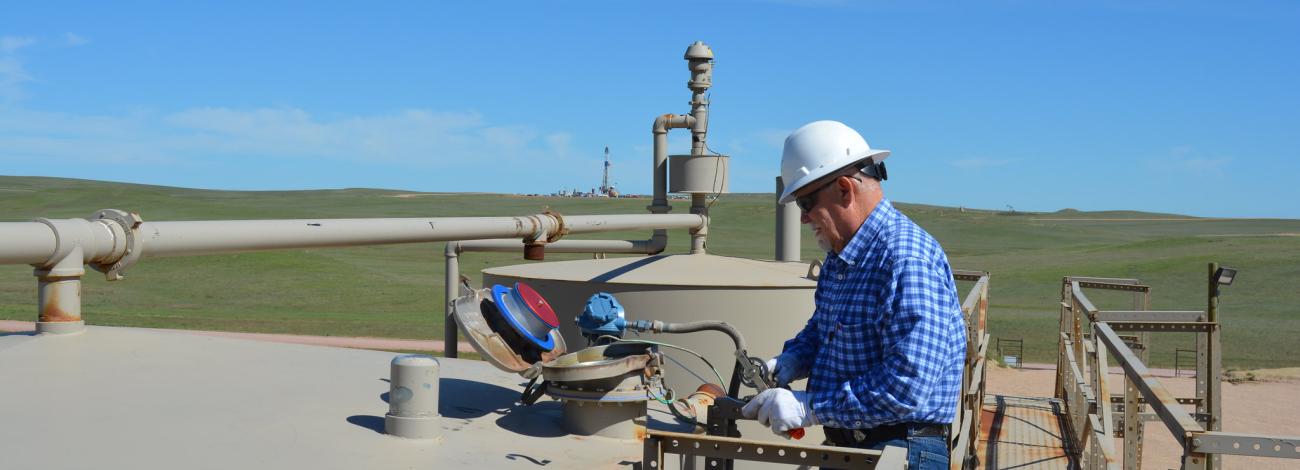 a man in a blue shirt and white hard hat inspects an opening in a metal structure