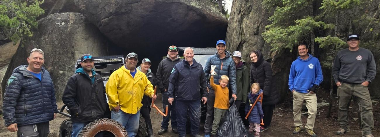 A group of people pose for a photo surrounded by trees and large boulders