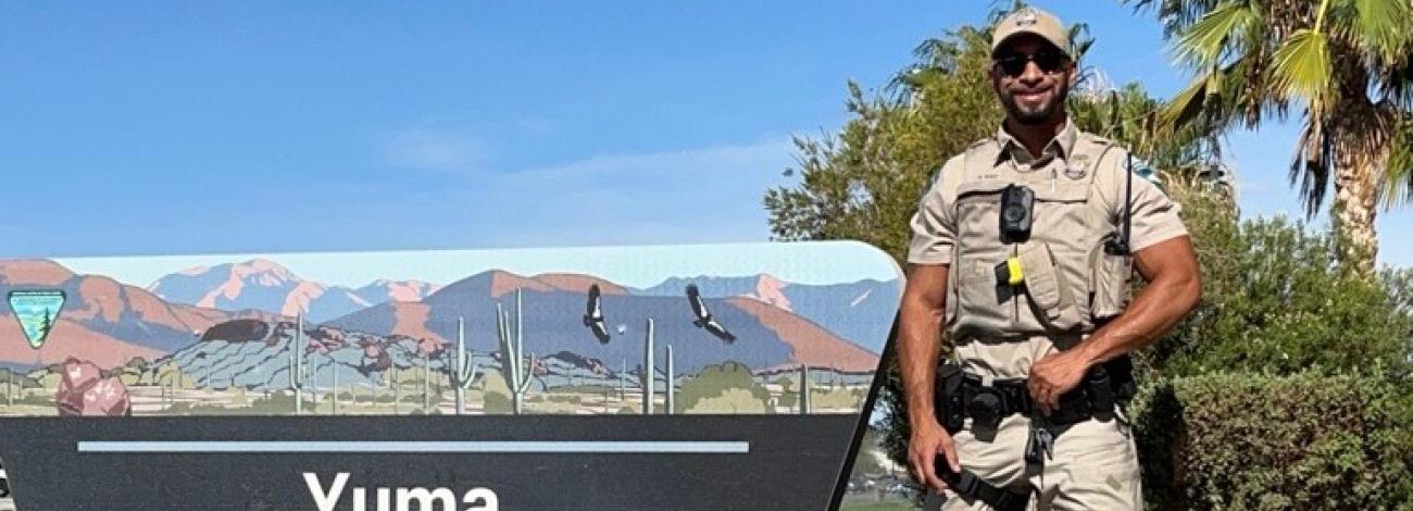 A uniformed BLM ranger stands to the right of the Yuma Field Office sign.