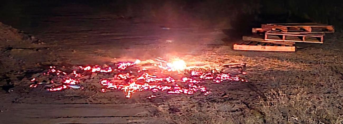 A smoldering bonfire next to some stacked pallets