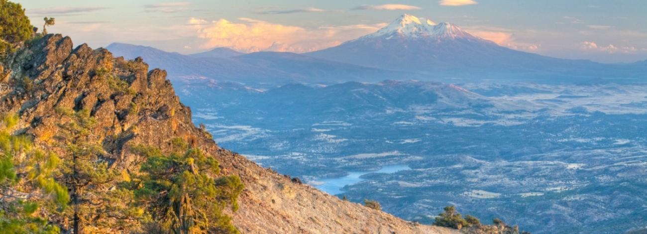 Mountain ridge with valley below and large mountain peak looming in the distance,