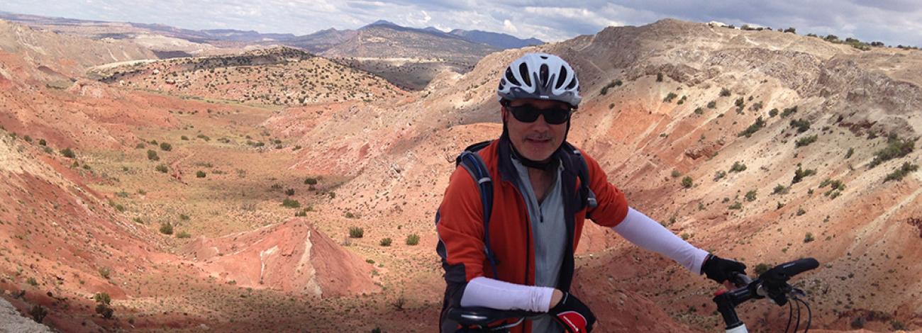 A cyclist standing in front of the red rock canyon at White Ridge Bike Trails