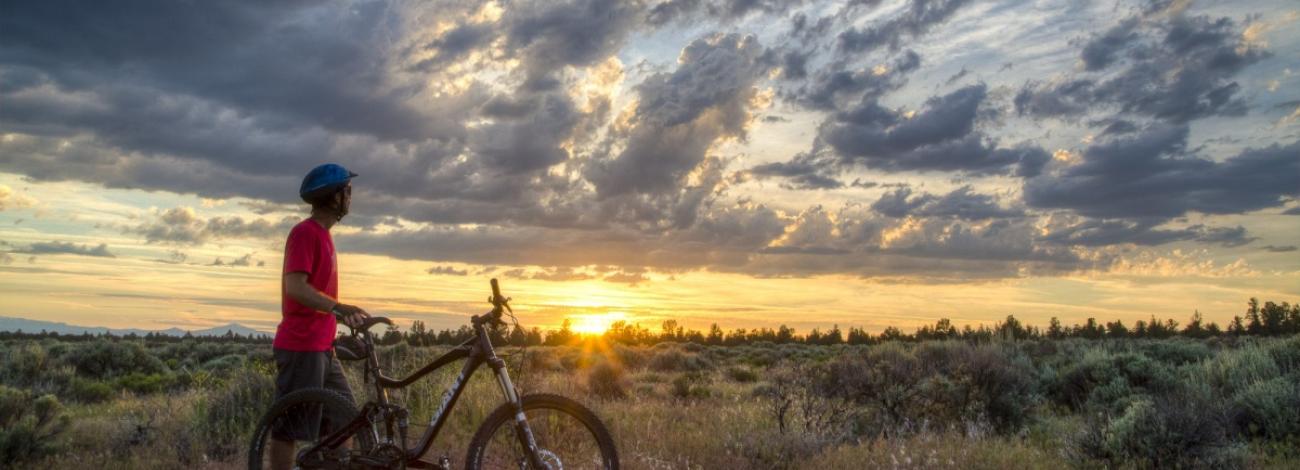 A man with his bike watches the sun behind the clouds at Cline Butte, Oregon. Photo by Bob Wick, BLM.