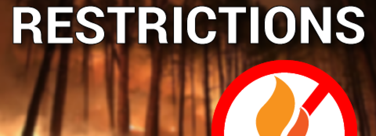 a wildfire burning in trees with the text Fire Restrictions