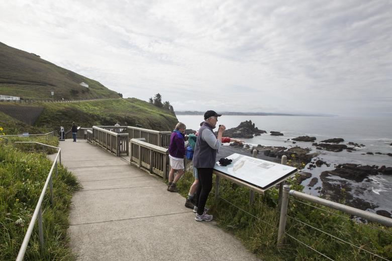 visitors with binoculars at a Yaquina Head overlook