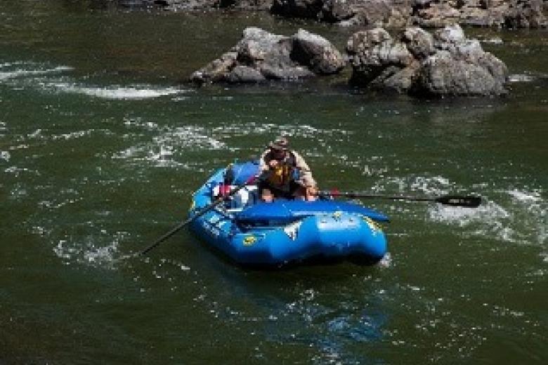 photo showing a person floating a craft on a river