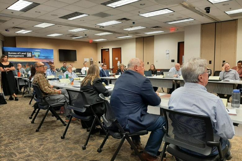 People in a conference room seated around a table. 