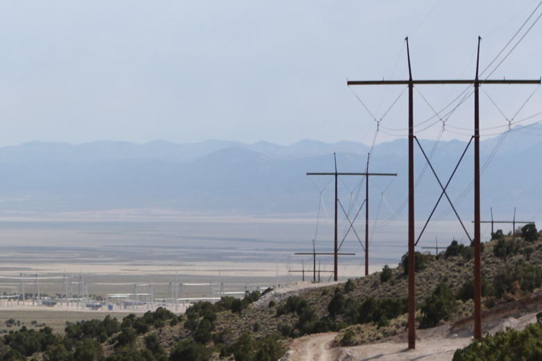 A transmission line extends across the landscape toward a power sub-station