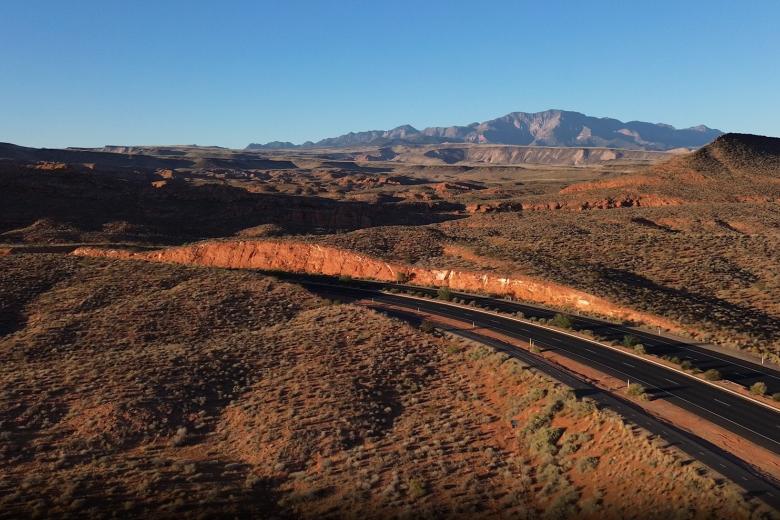 Desert landscape with road and mountains in the distance in Washington County, Utah.