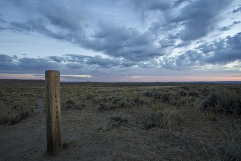 Post on open sagebrush plain marking historic trails junction.