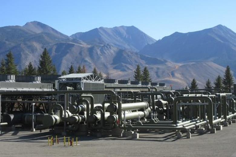 A geothermal plant in front of large mountains. 