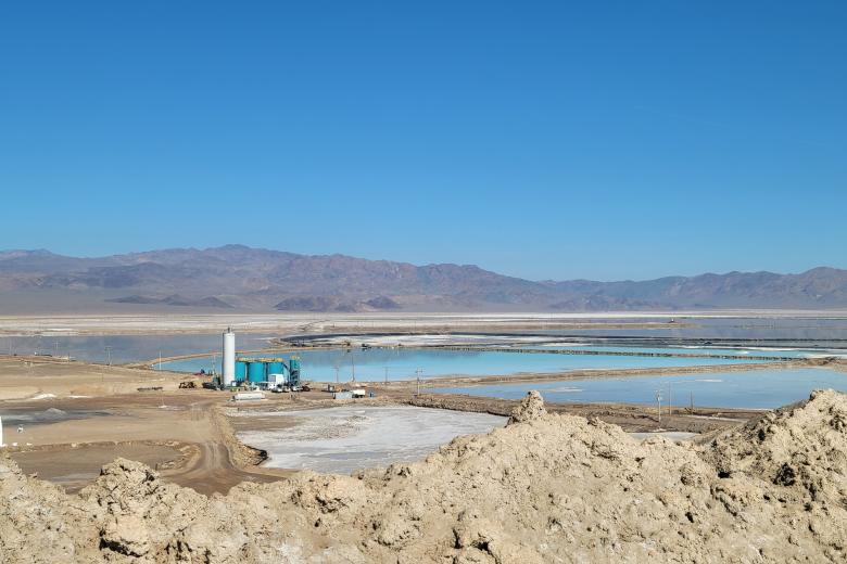 Towers and other mining related structures are alongside manmade ponds with mountains in the background.