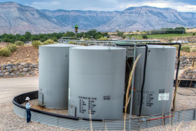 A technician stands beside a BLM Colorado oil and gas well pad.