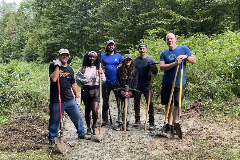 People standing with shovels and tools on a dirt path