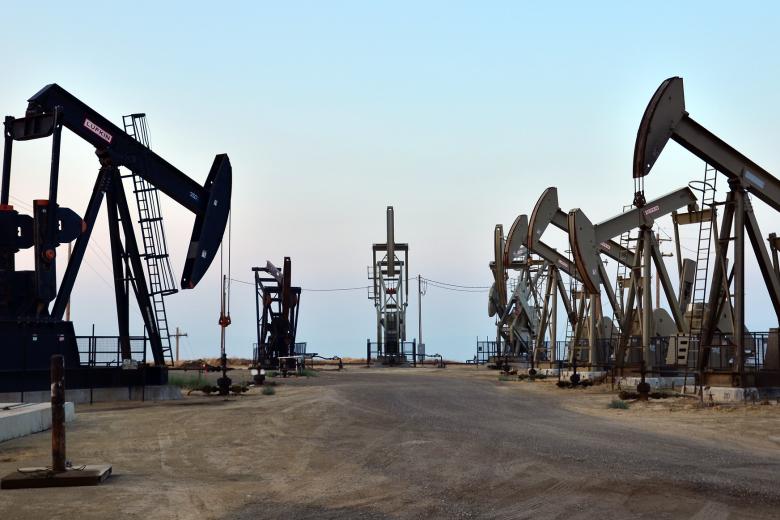 Seven oil and gas pump jacks moving up and down in the San Joaquin Valley, California.