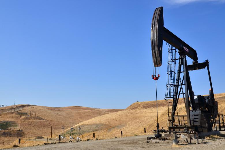 An oil derrick in a dry grassy hill