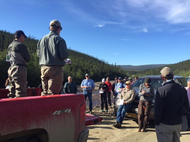 Alaska Resource Advisory Council members and BLM staff listen to presenters standing in the back of a pick-up truck at Jack Wade Creek project