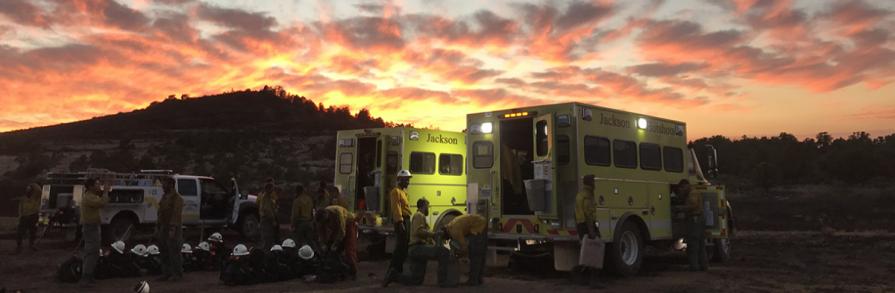 Jackson fire crew standing near engine at sunset 