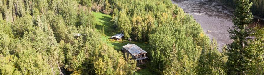 Steele Creek Community aerial view showing 3 wood structures along the Fortymile River