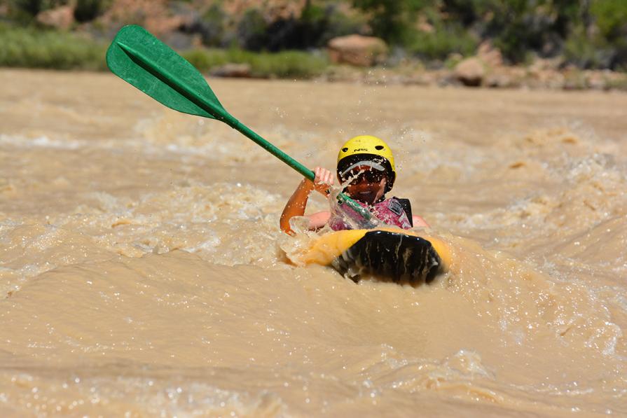 A woman paddles through whitewater rapids in her inflatable kayak. 