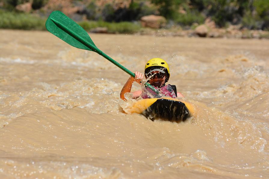 A woman paddles through whitewater rapids in her inflatable kayak.