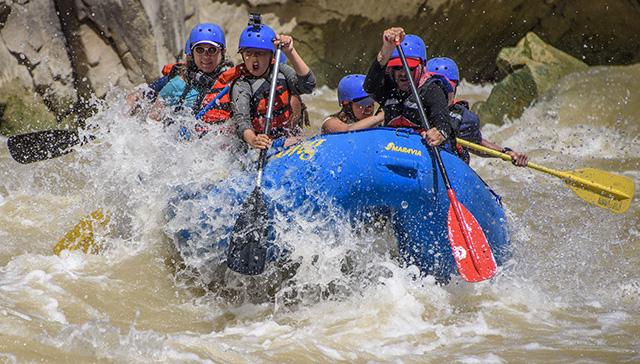 A group enjoys paddling through the whitewater rapids in the Westwater Canyon.