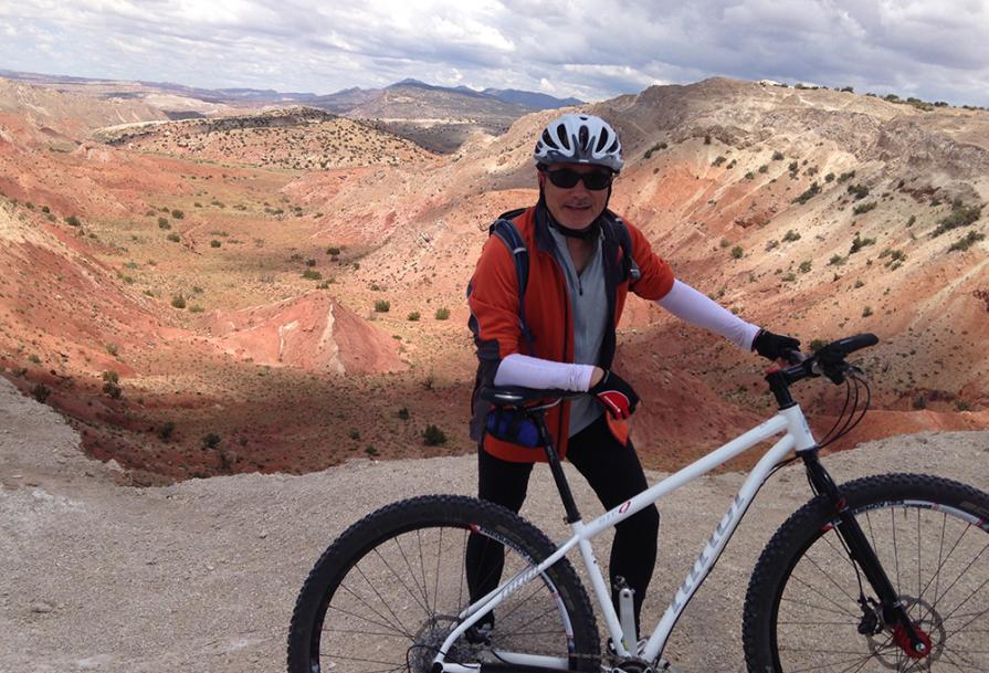 A cyclist standing in front of the red rock canyon at White Ridge Bike Trails