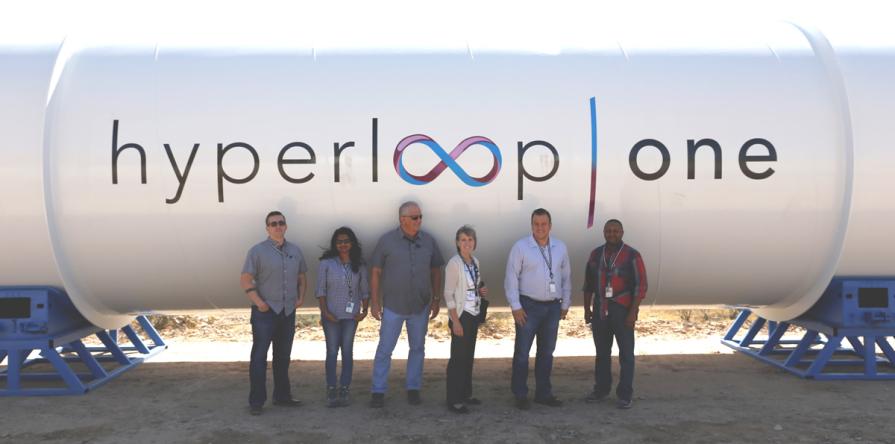 Six Las Vegas Field Office (LVFO) employees in front of a Hyperloop One tube.