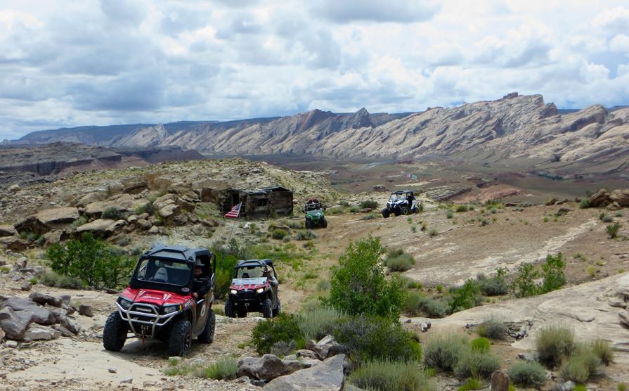 Four OHV's drive past a historical building outside the San Rafael Swell.