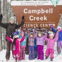 Instructor and children in front of the snowy Science Center sign