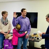 Man gets sworn in with woman and 2 children standing by.