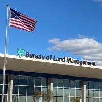 an office building with an American flag flying outside. The building sign reads Bureau of Land Management, Managing your public lands