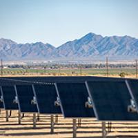 An array of photovoltaic panels in the desert with mountains in the background.