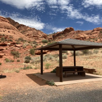 View of Red Cliffs Campground campsite with grill, shade shelter and picnic table.
