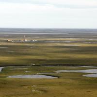 Small area of industrial development structures is surrounded by open green tundra and pockets of pooled water.  Photo by Judy Patrick, courtesy of ConocoPhillips