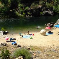 Beach tents line the shores of the forested Merced river.