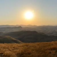 Dry grassy hills with the sun in the background