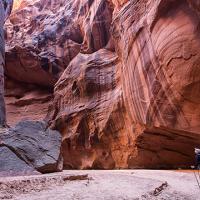 a backpacker walks on a gravel surface surrounded by steep canyon walls
