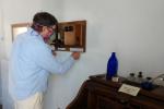 a man installs a candlestick-style telephone onto a wall