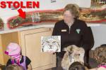 "Stolen" and arrow pointing to highlighted mammoth tusk on the counter behind a Science Center Instructor teaching kids