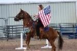 Woman on horse in an arena with a flag. 