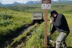 Man digging near sign post.