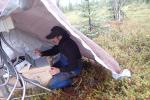 Man using computer under a tarp