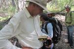 Jack Barnitz looking down at a device he is holding in the woods