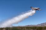 Single engine airtanker flying and dropping water on the landscape below