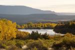 The Green River winding through the landscape of mountain ranges and trees with leaves changing colors in autumn. 