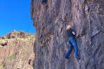 Two students are climbing the rock face while two staff members are holding their ropes below