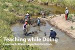 Five people standing in a large creek cleaning out debris. One person stands on the bank to help take debris.