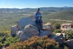 Alexia Williams, who is wearing hiking gear, leans up against a large rock.