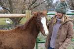 Woman standing with young horse. 